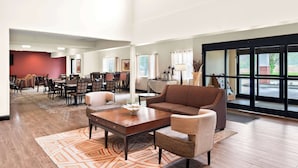 A spacious lobby with a brown sofa, a coffee table, and a dining area with chairs and tables. - Best Western Palmyra Inn & Suites (Palmyra)