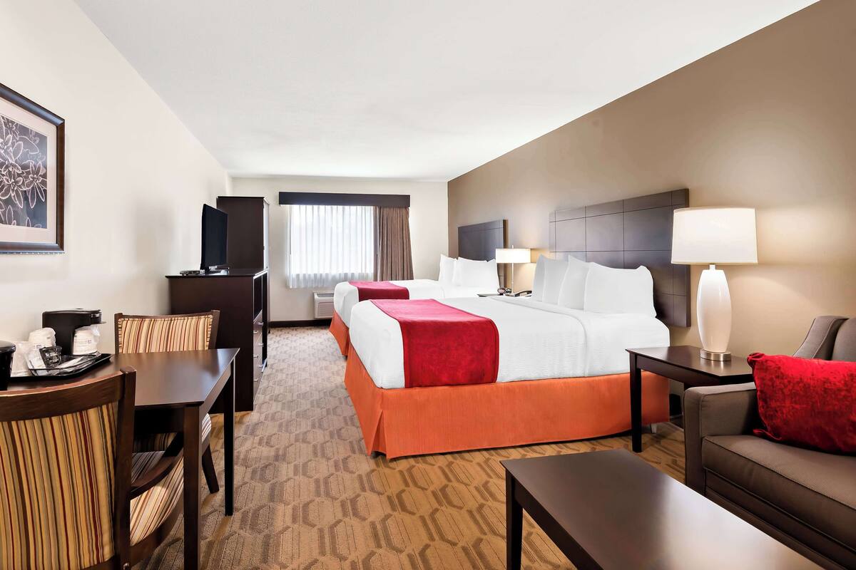 A hotel room with a bed, a desk with a chair, a sofa, a lamp, and a TV.