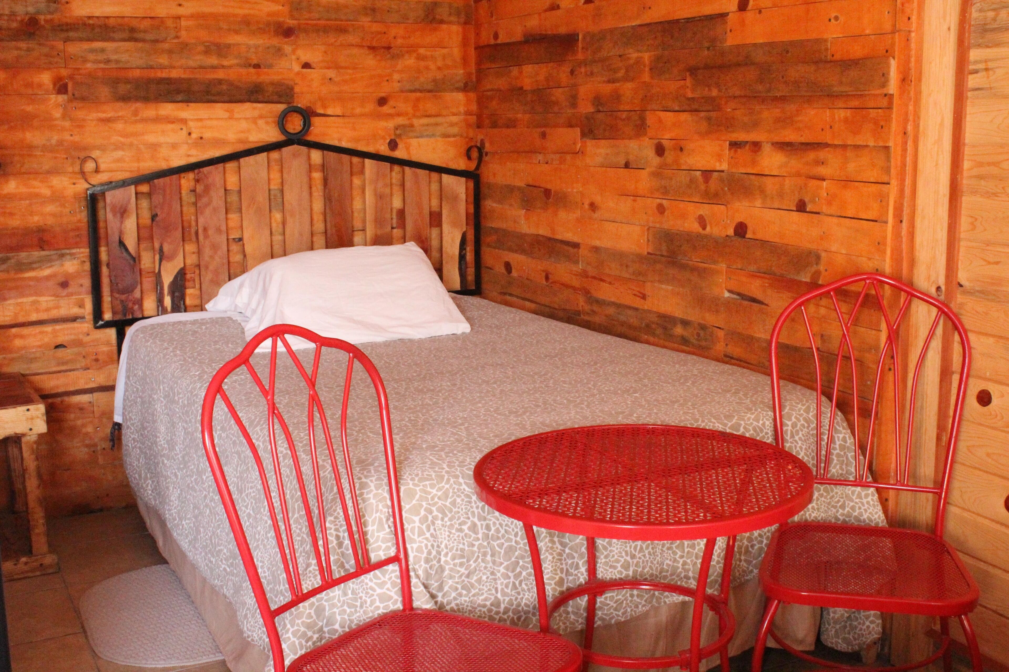 Une pièce de style cabane en bois, comprenant un lit, une petite table et deux chaises.