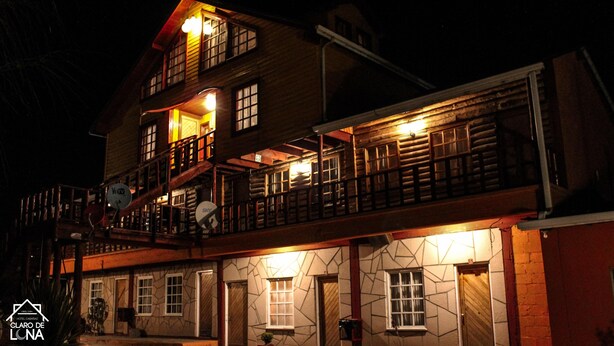 A two-story log cabin-style building with a balcony and a stone facade.