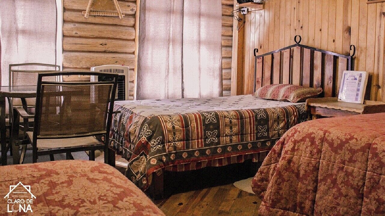 Accogliente camera in legno con un letto, un tavolo e delle sedie.