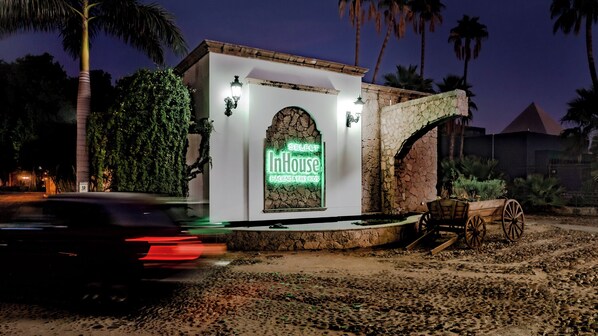 Un edificio con un letrero de neón que dice "Select InHouse Hacienda Tres Rios" de noche.