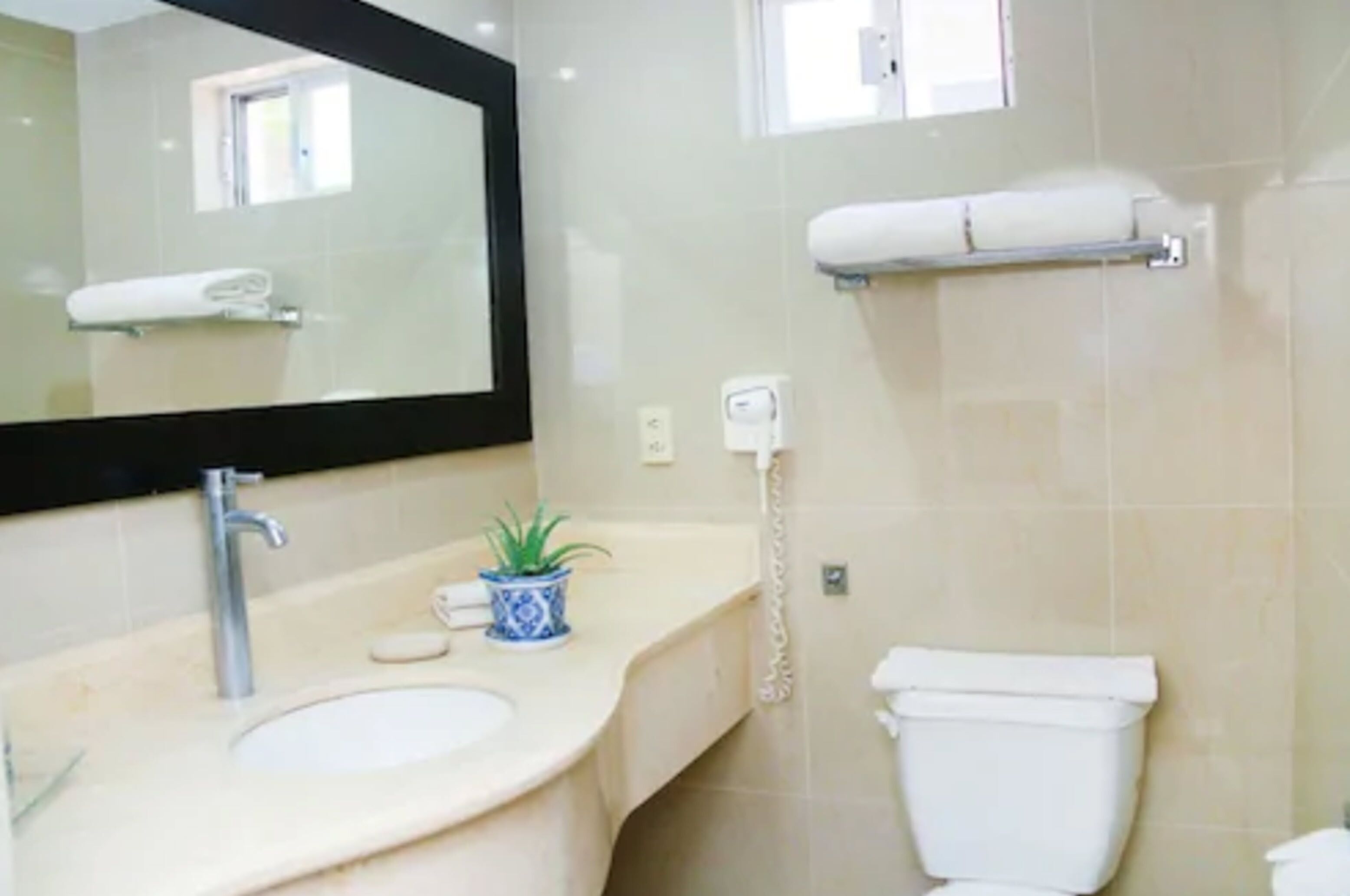 Ein Badezimmer mit Waschbecken, Spiegel, Toilette und Handtuchhalter.