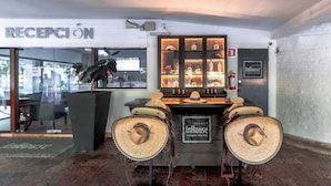 A reception area with a sign reading "RECEPCIÓN" and a display case with bottles. There are two chairs with sombreros in front of the display case.