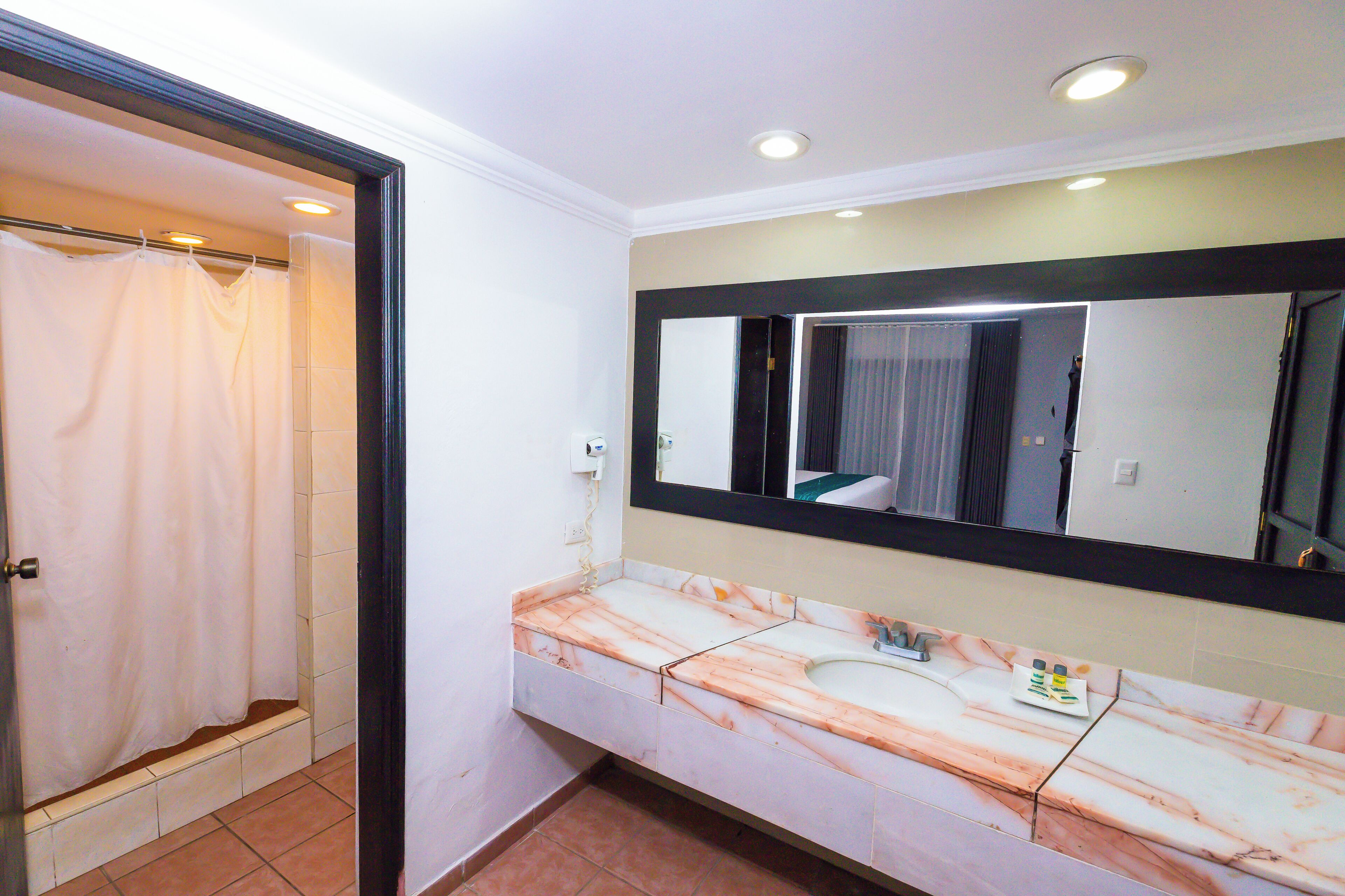 A bathroom with a marble sink, a large mirror, and a shower curtain.