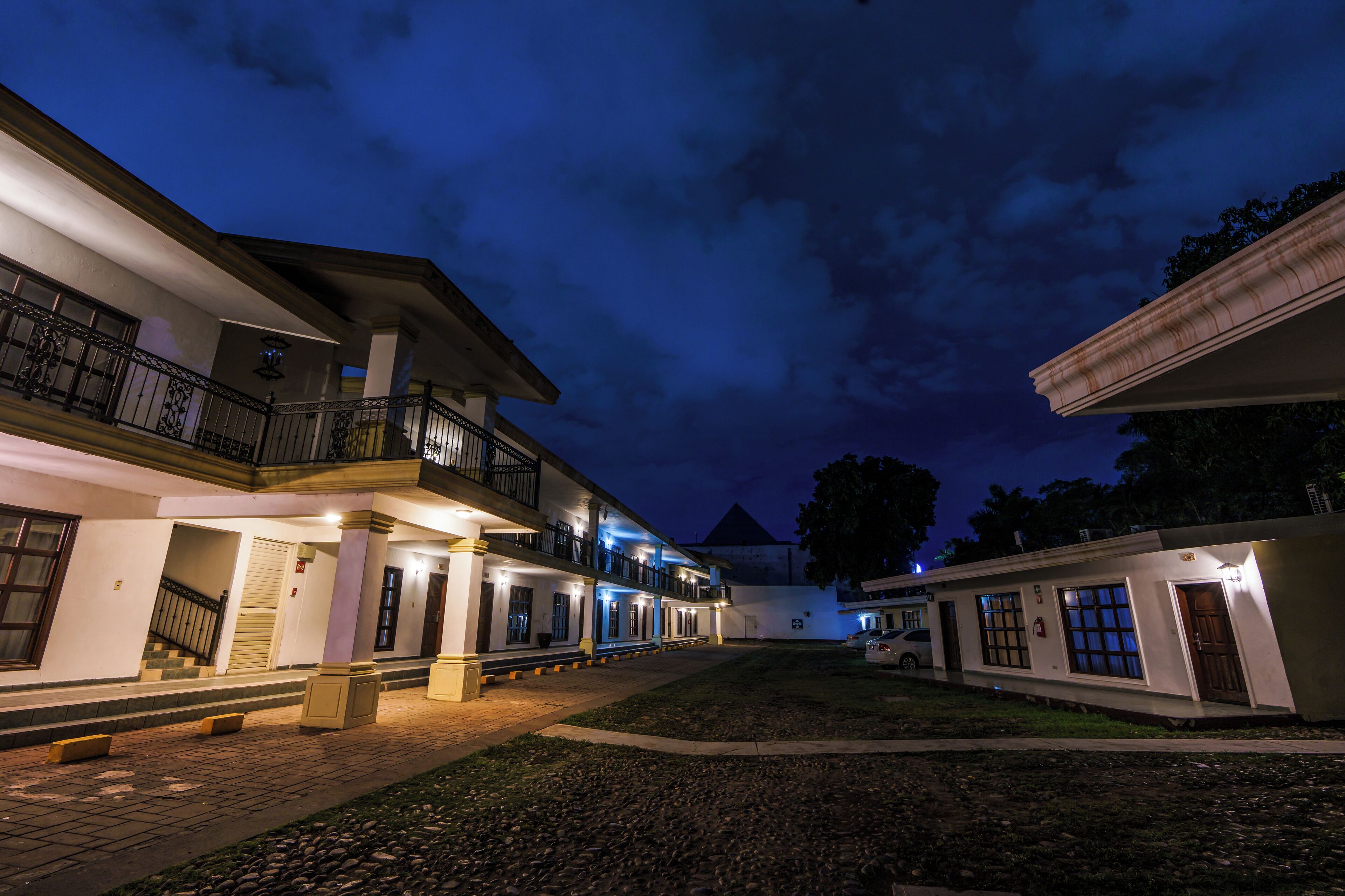 A hotel with a covered outdoor area, multiple balconies, and a well-lit entrance.