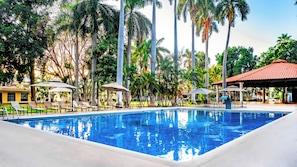 Een buitenzwembad, parasols bij het zwembad en ligstoelen