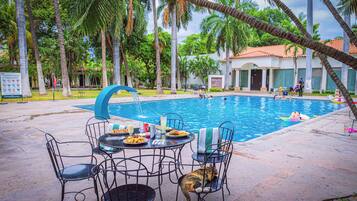 Alberca al aire libre, sombrillas en la alberca y camastros