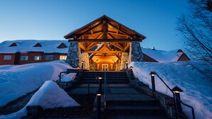 A lodge entrance with a stone facade, wooden beams, and a snow-covered landscape. - Talkeetna Alaskan Lodge (Talkeetna)