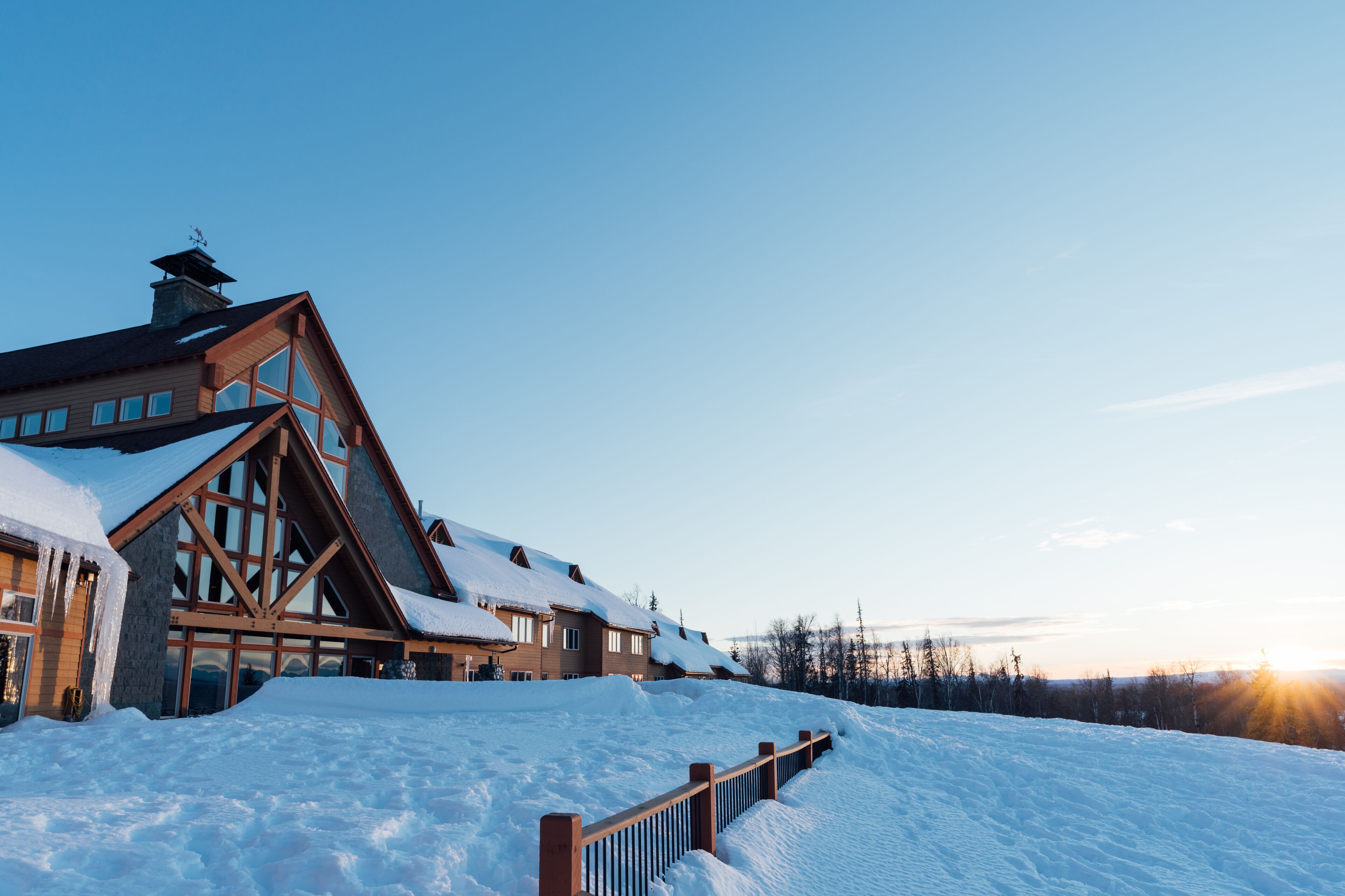 A large lodge with a prominent wooden facade and multiple windows, surrounded by snow.