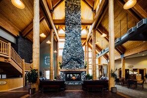 A spacious lobby with a stone fireplace, wooden beams, and seating areas. - Talkeetna Alaskan Lodge (Talkeetna)