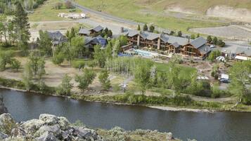 A lodge with multiple cabins, a swimming pool, and a river in the foreground.
