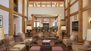 A spacious living room with a large sofa, armchairs, and a coffee table. There is a kitchen area with wooden cabinets and a dining table. - The Lodge at Canyon River Ranch (Ellensburg)