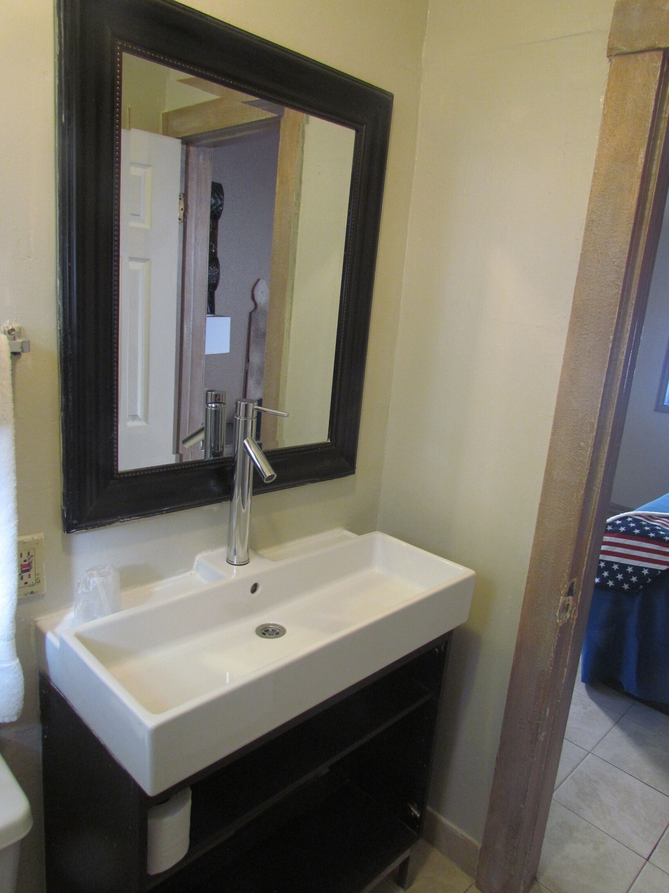 A bathroom with a white sink, a mirror, and a towel rack.
