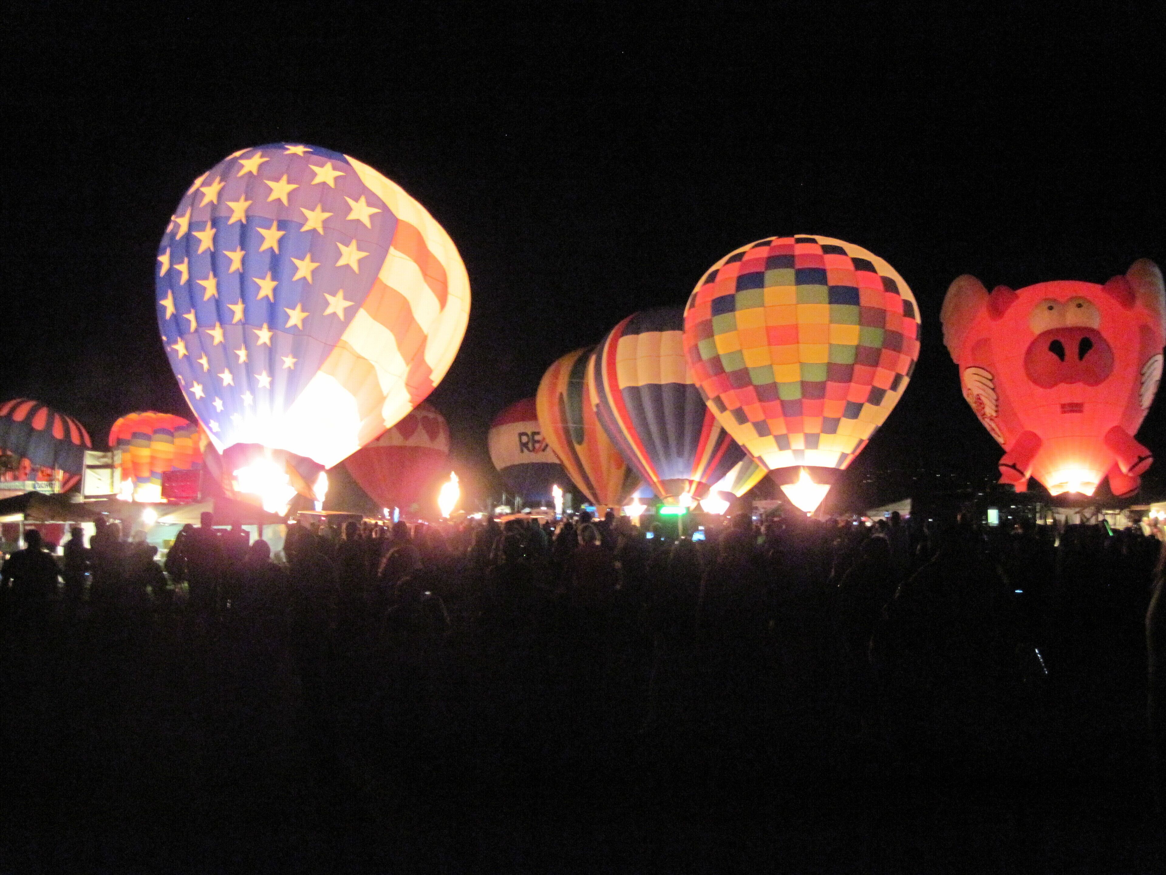 Ein nächtliches Festival mit Heißluftballons in verschiedenen Formen und Farben.