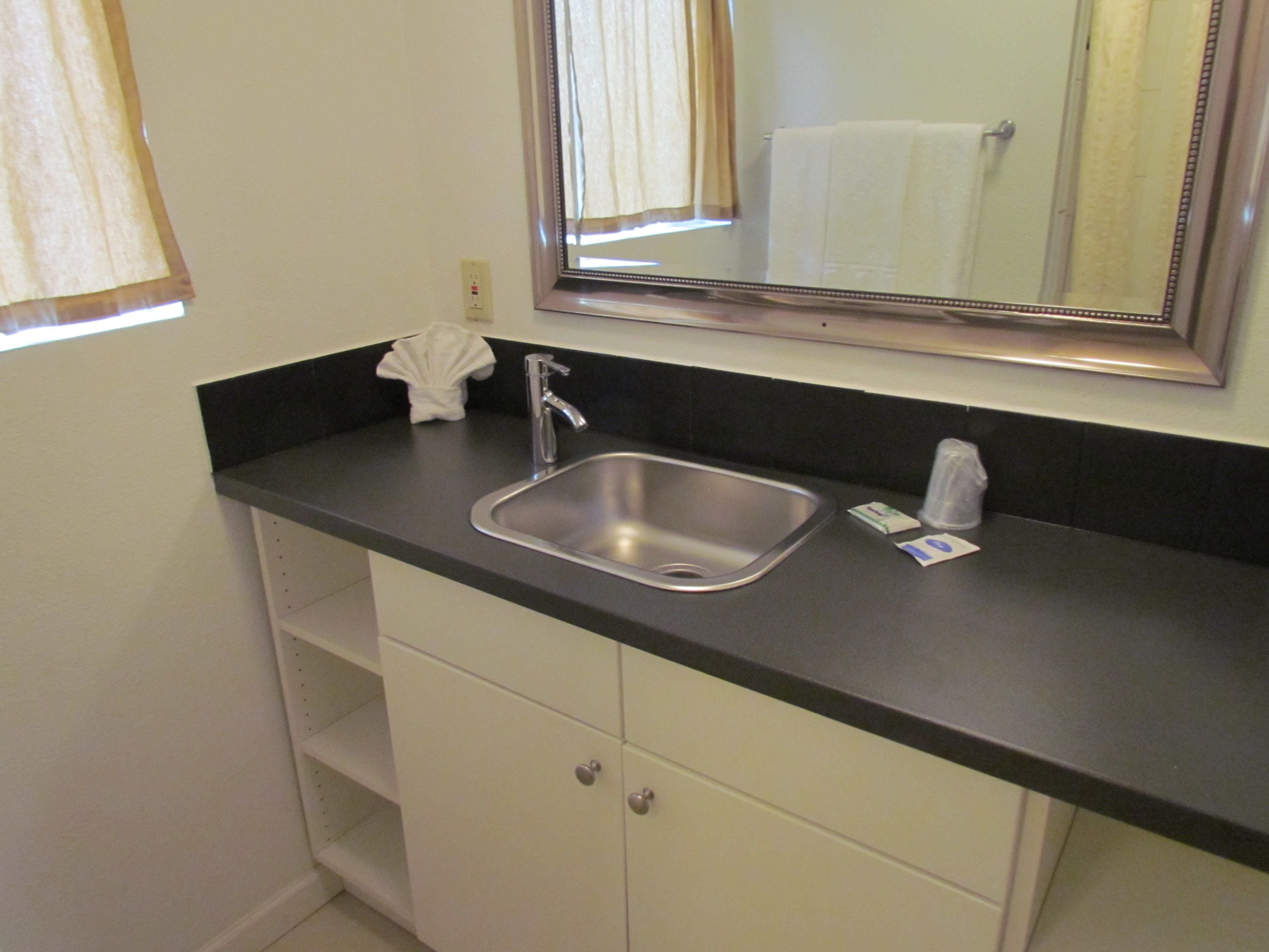 A bathroom with a sink, mirror, and towel rack.