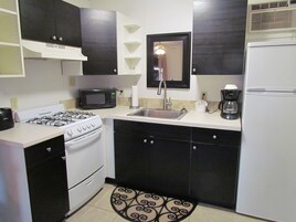 Cocina compacta con estufa a gas, microondas, lavabo y refrigerador.