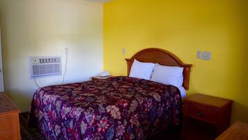A room with a bed, a nightstand, a dresser, and a wall-mounted air conditioner.