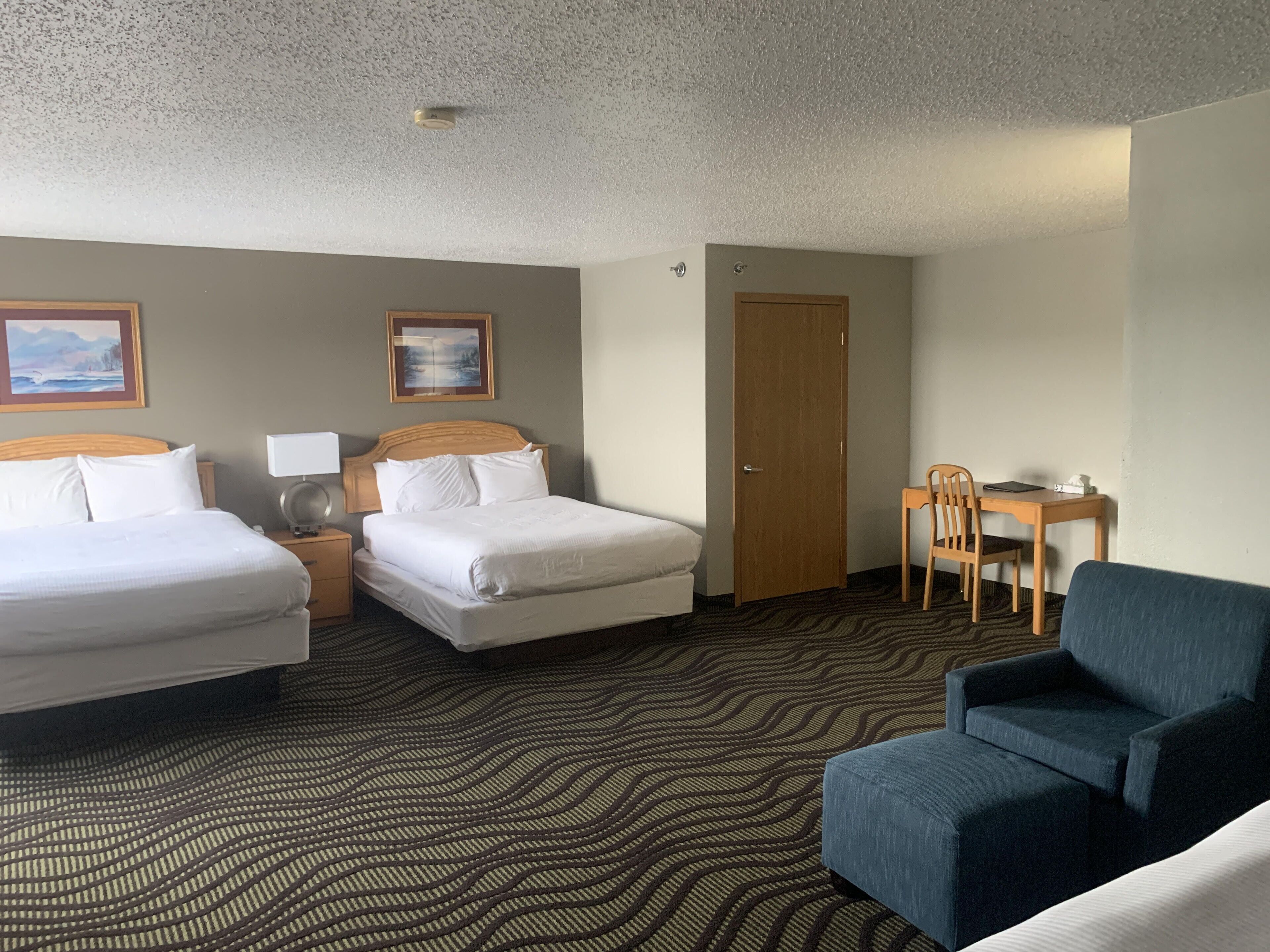 Une chambre d’hôtel avec deux lits, un bureau, une chaise et un canapé.