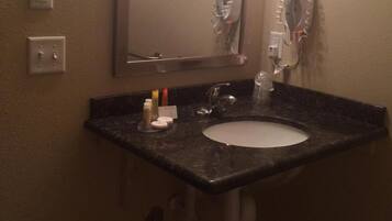 A bathroom with a sink, mirror, hairdryer, and towel rack.