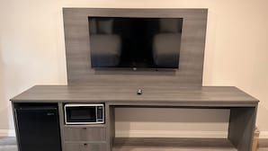A modern entertainment center with a flat-screen TV, a built-in microwave, and a small refrigerator. - Five Star Inn West Covina (West Covina)