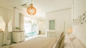 A spacious bedroom with a large bed, a vanity with a mirror, and a view of the outdoors. - Green Gallery (Hua Hin)