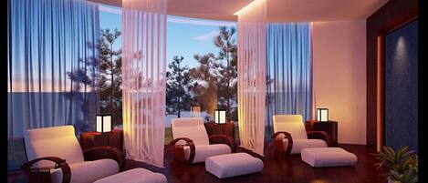 A modern hotel room with large windows, white upholstered sofas, and a wooden floor.