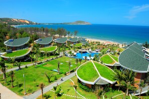 Un resort con varias edificaciones, una piscina y vista a la playa.