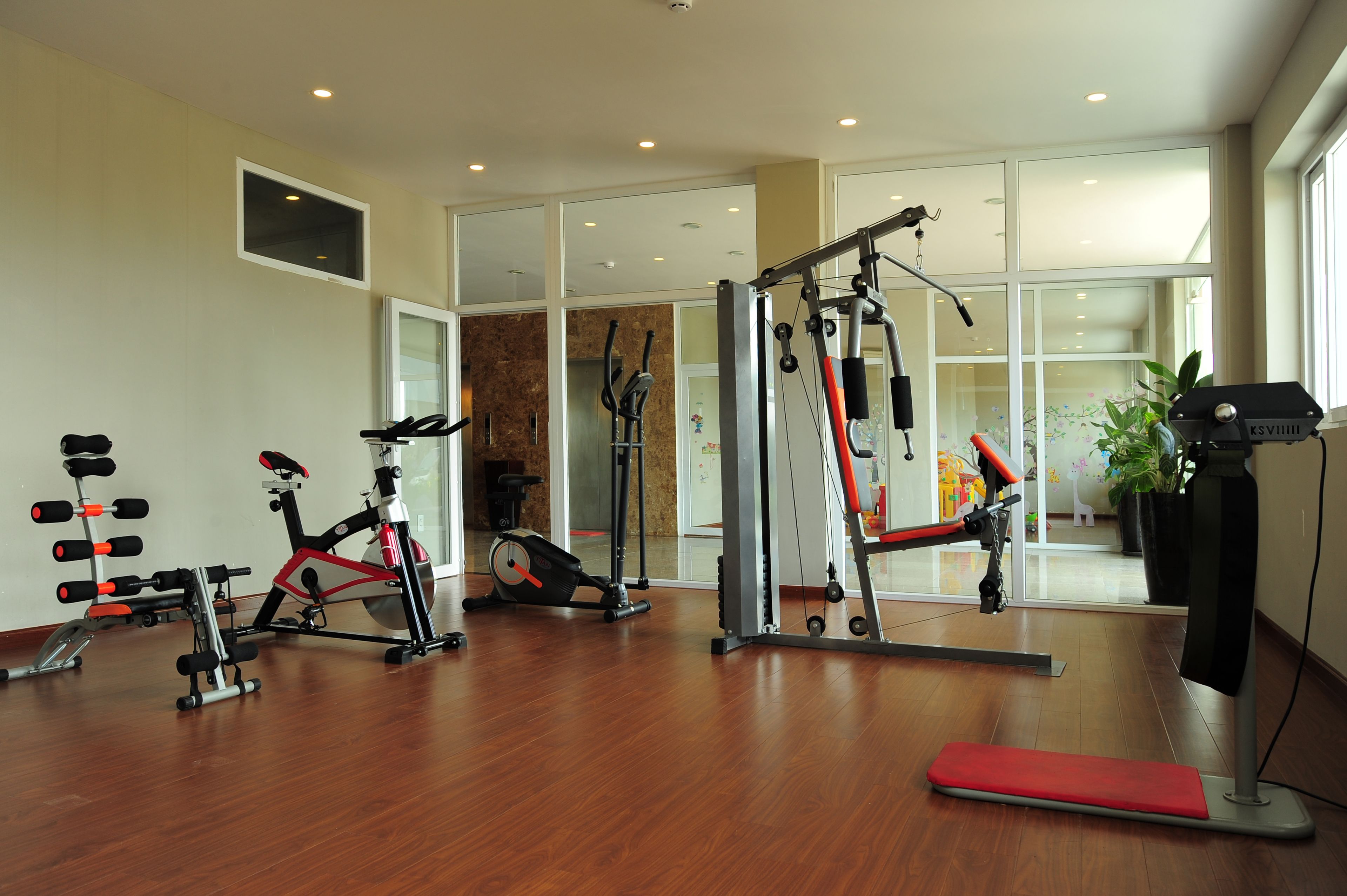 A spacious gym with various exercise equipment, including a stationary bike, elliptical, and weight machines.