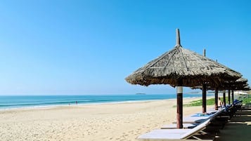 Pantai pribadi, pasir putih, kursi berjemur, dan payung pantai