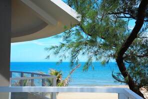 A balcony with a view of the ocean and a pine tree. - Sandunes Beach Resort & Spa (Phan Thiet)