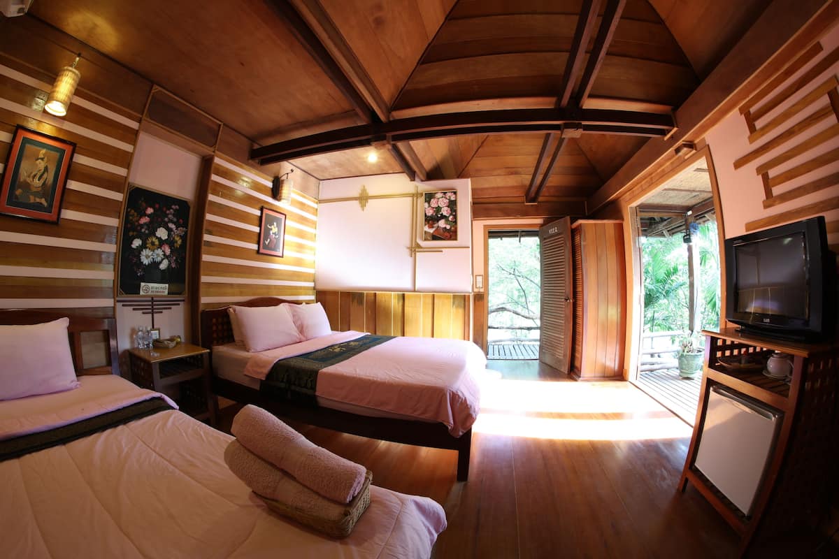 A hotel room with two beds, wooden ceiling, and a television on a stand.