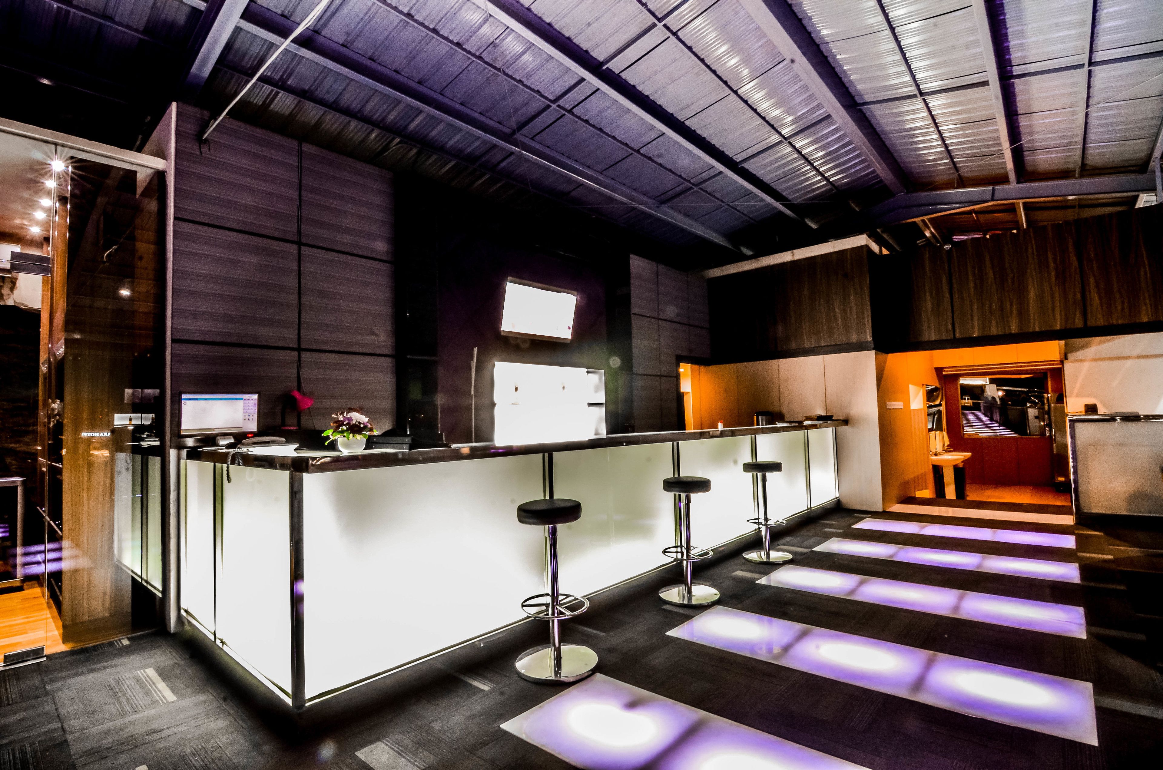 Un área de bar moderna con una barra, taburetes y una pantalla de televisión.