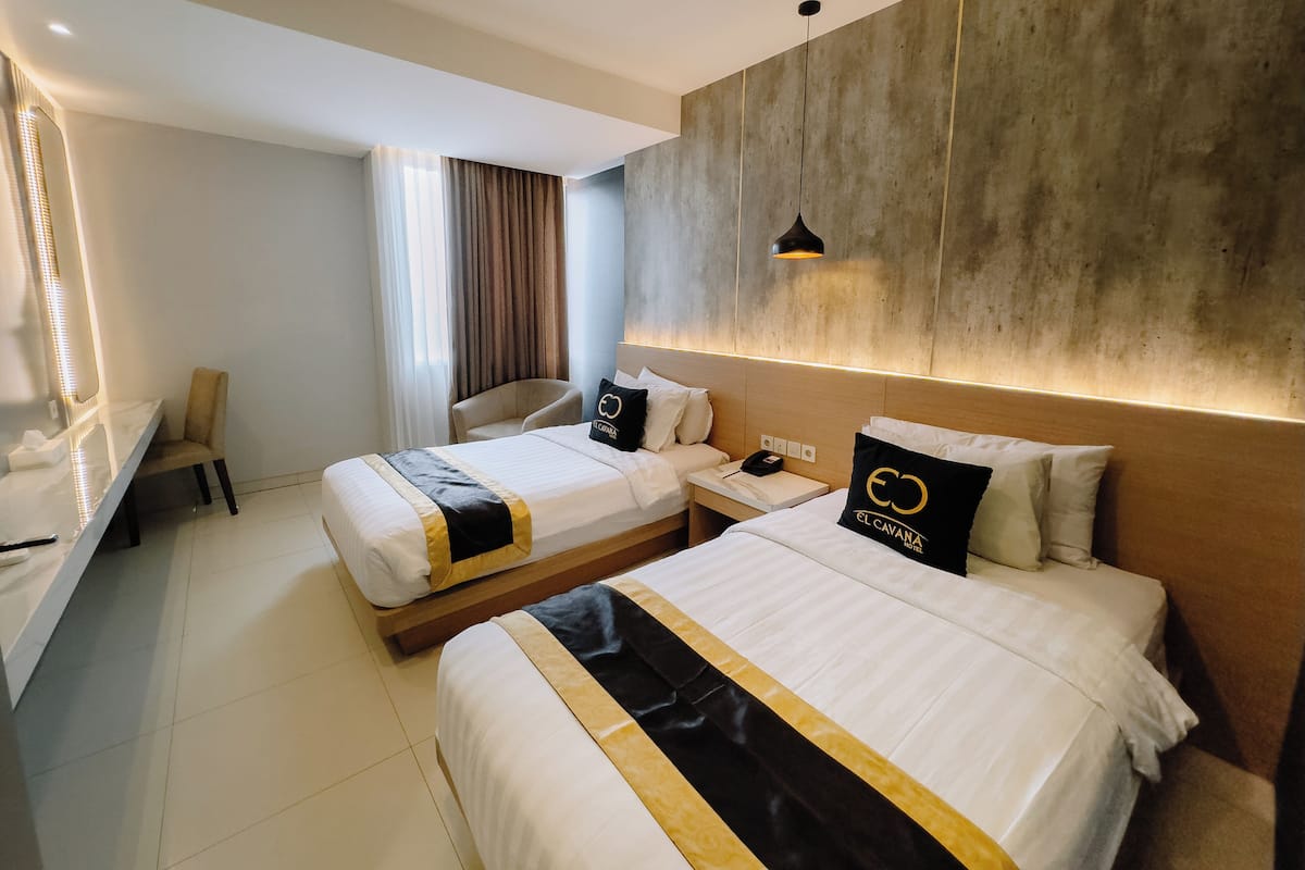 A hotel room with two beds, a desk, a chair, and a large mirror.