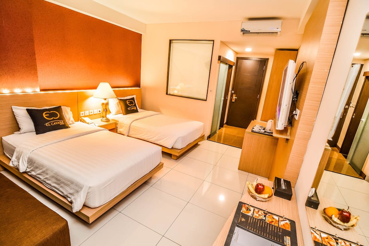A hotel room with two beds, a desk with a menu, and a mirror.