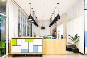A reception desk with a geometric design, multiple pendant lights, and a potted plant. - Hotel Citradream Bandung (Bandung)