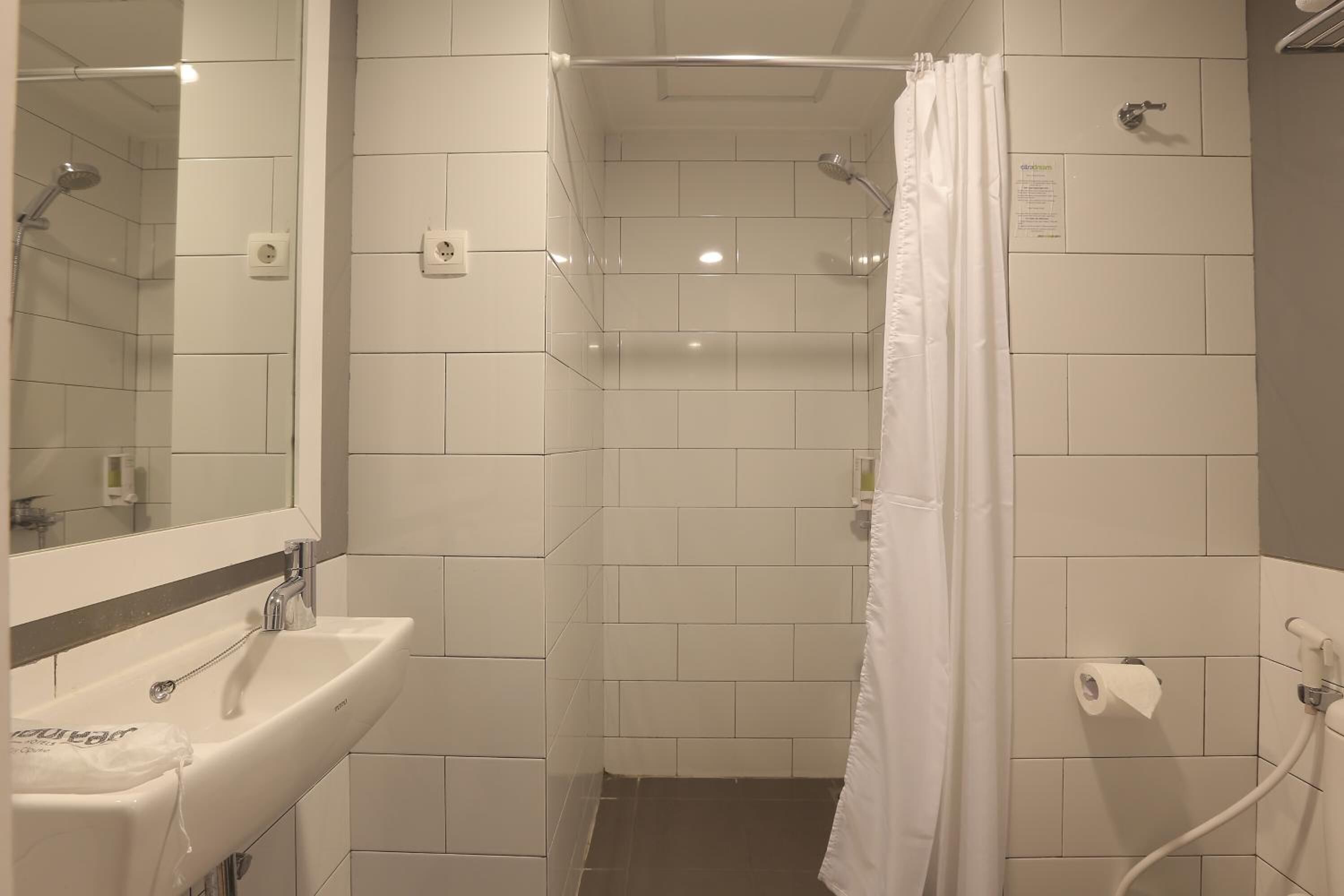 A bathroom with a sink, mirror, shower, and toilet.