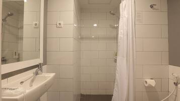 A bathroom with a sink, mirror, shower, and toilet.