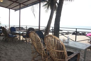 A beachside seating area with wicker chairs and a table, overlooking the ocean. - Sea View Resort (Ashvem)