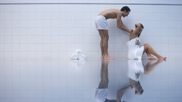 A couple in a bathroom with a tiled wall and a reflection on the floor. - Gran Hotel Balneario de Cestona (Zestoa)