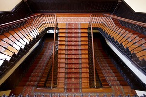 Una imponente escalera con barandillas ornamentadas y alfombra estampada.