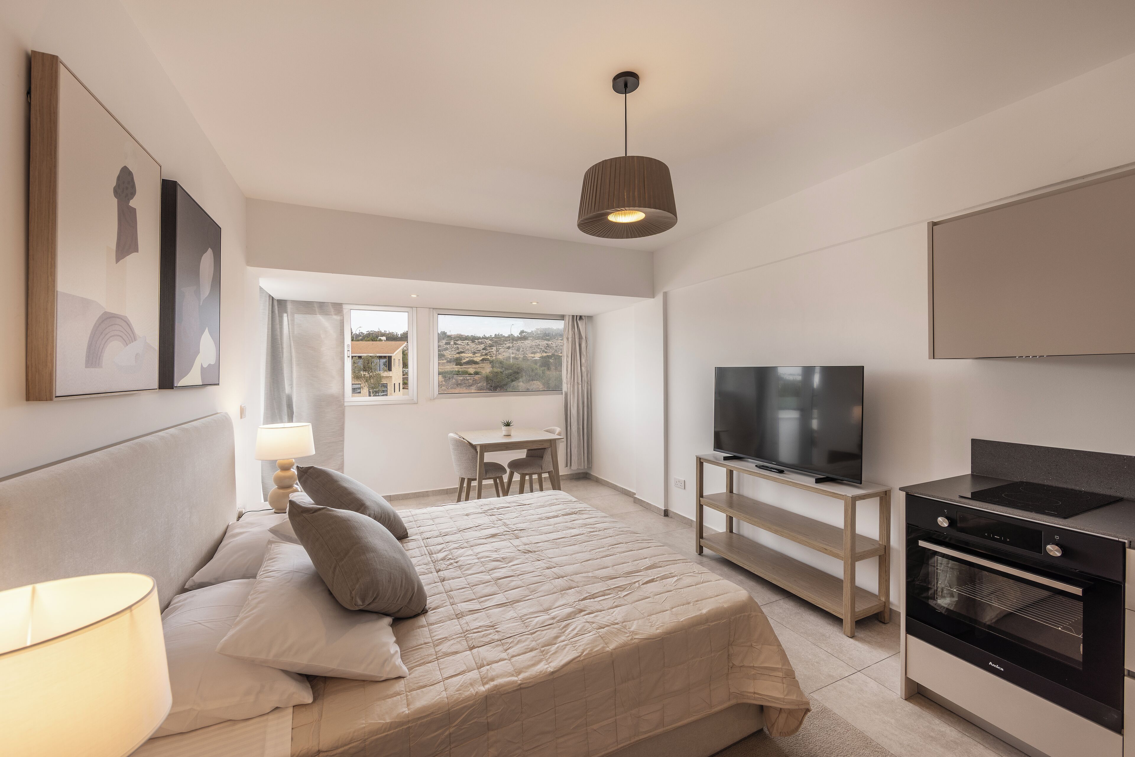 Een moderne slaapkamer met een bed, bedlampje, televisie en een inbouwoven.