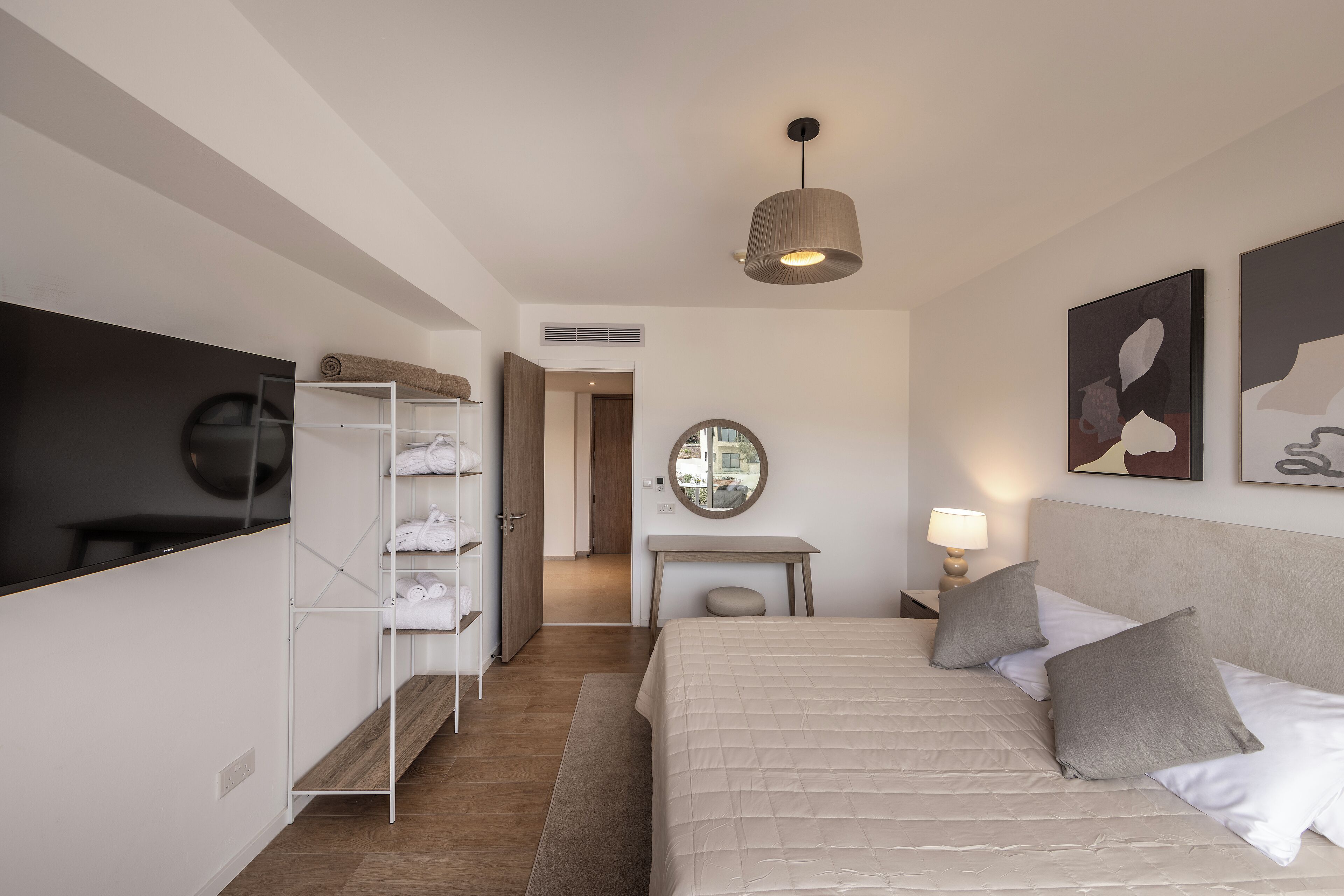 Una habitación de hotel moderna con una cama, un escritorio, un armario y un espejo.