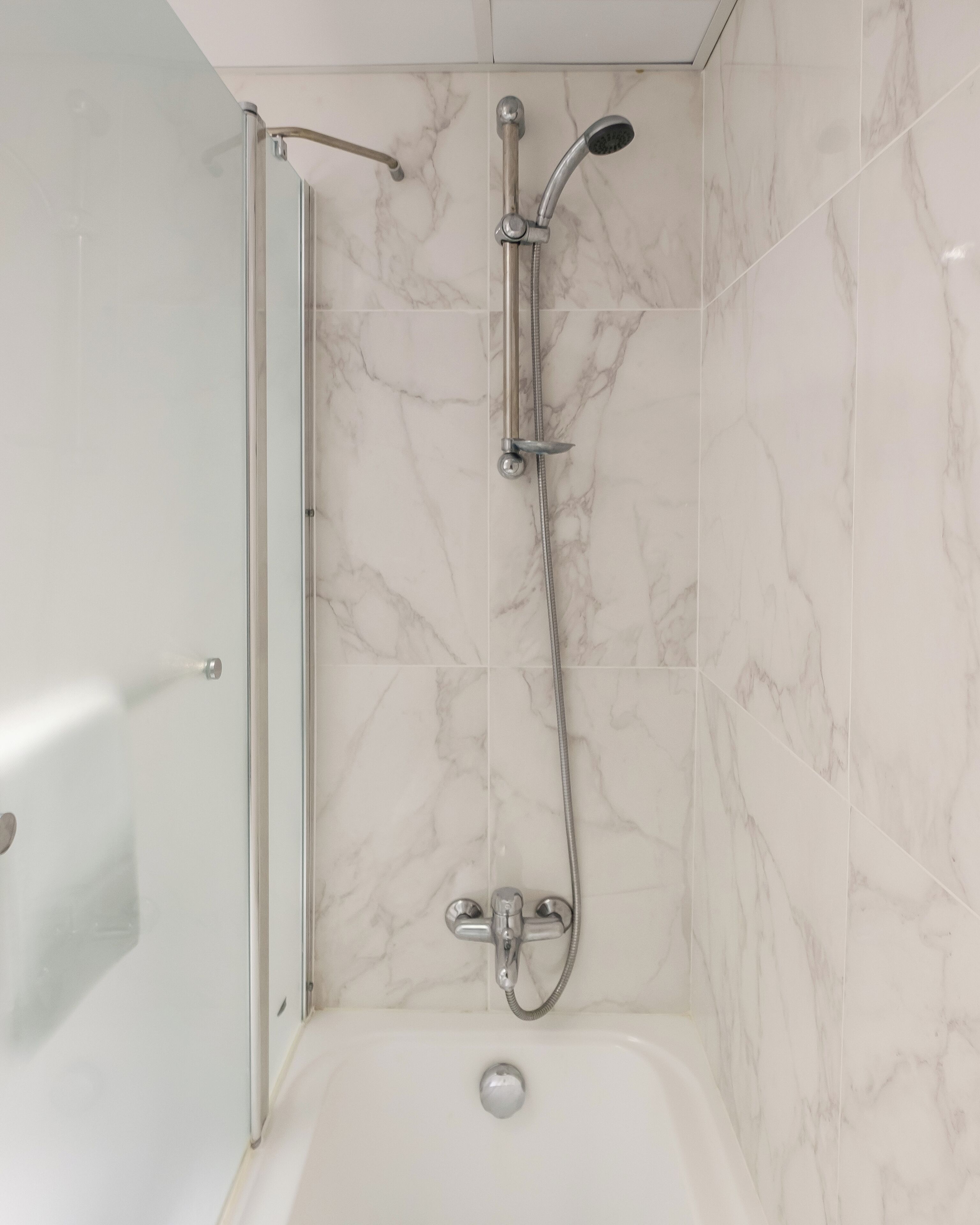 Un baño con ducha, bañera y mampara de vidrio.