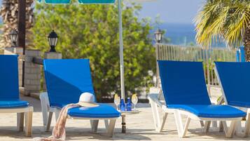 Un espace aménagé au bord de la piscine, avec des chaises longues bleues et un parasol turquoise.