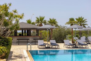Ein Poolbereich mit Liegestühlen, Sonnenschirmen und einer Bar.