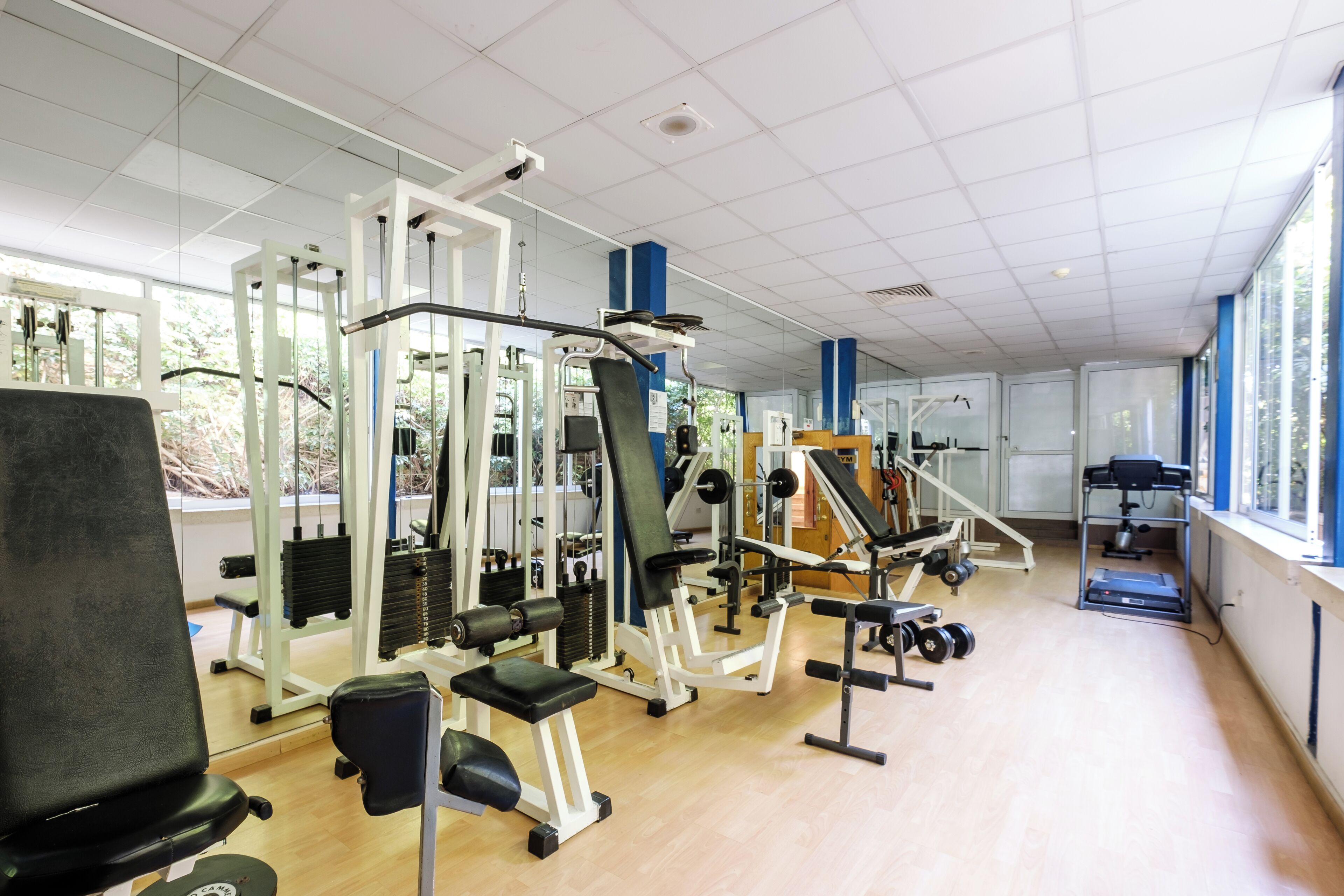 Une salle de sport équipée de divers appareils d’exercice, de bancs et d’un tapis de course.