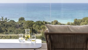 A balcony with a view of the ocean, a table with glasses and a vase, and a wicker chair. - Cyprotel Florida Hotel (Ayia Napa)
