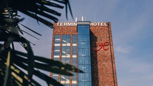 A tall brick building with a sign reading 'TERMIN HOTEL' and a red logo.