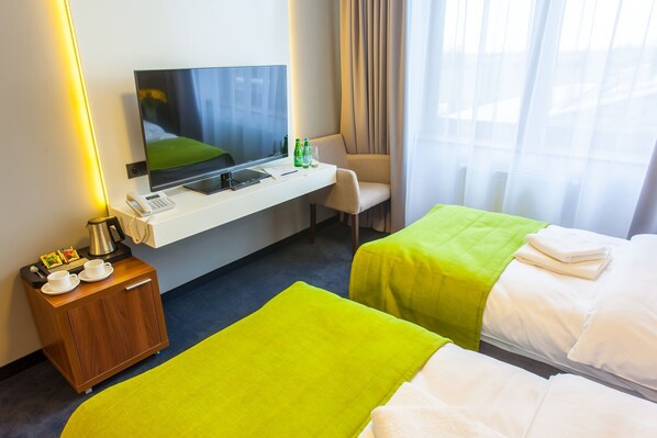 A hotel room with two beds, a desk with a TV, a telephone, and a minibar.